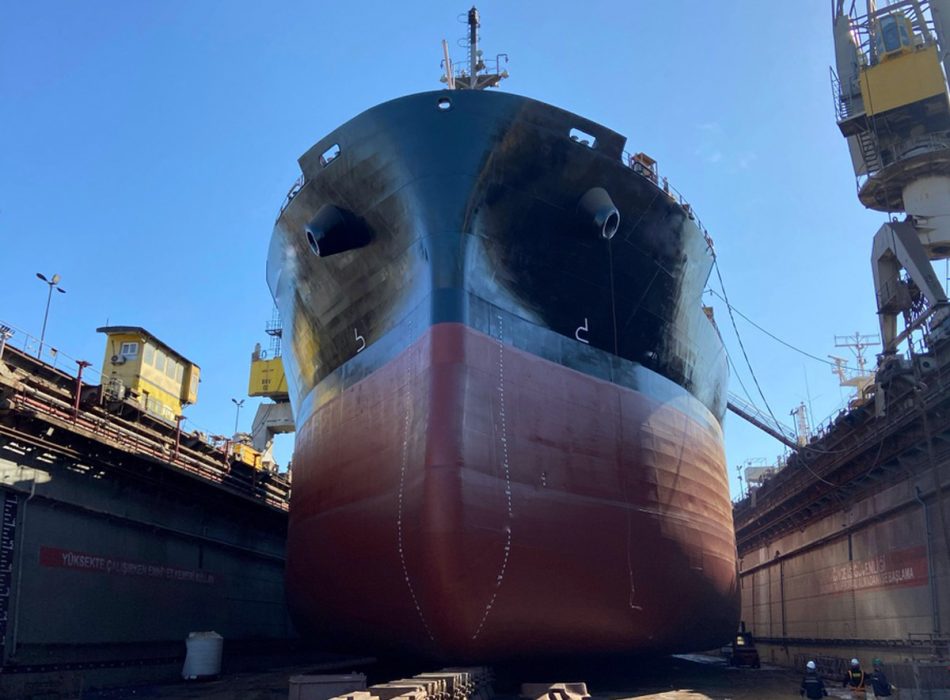 Large vessel docked at Yalova shipyard with workers and cranes visible.