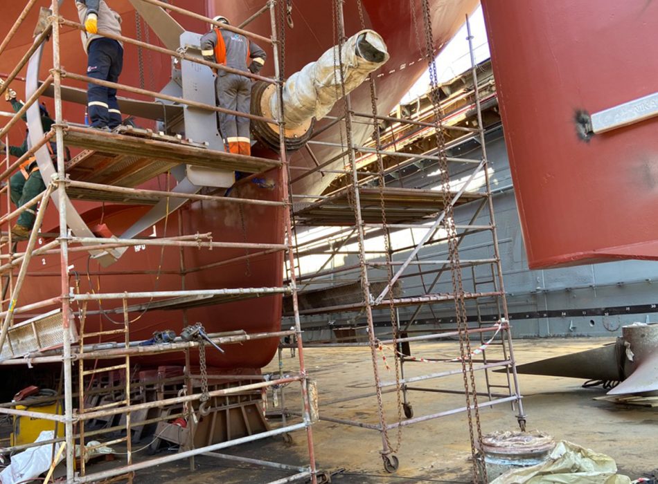 Technicians working on a ship's propulsion system at the dry dock.