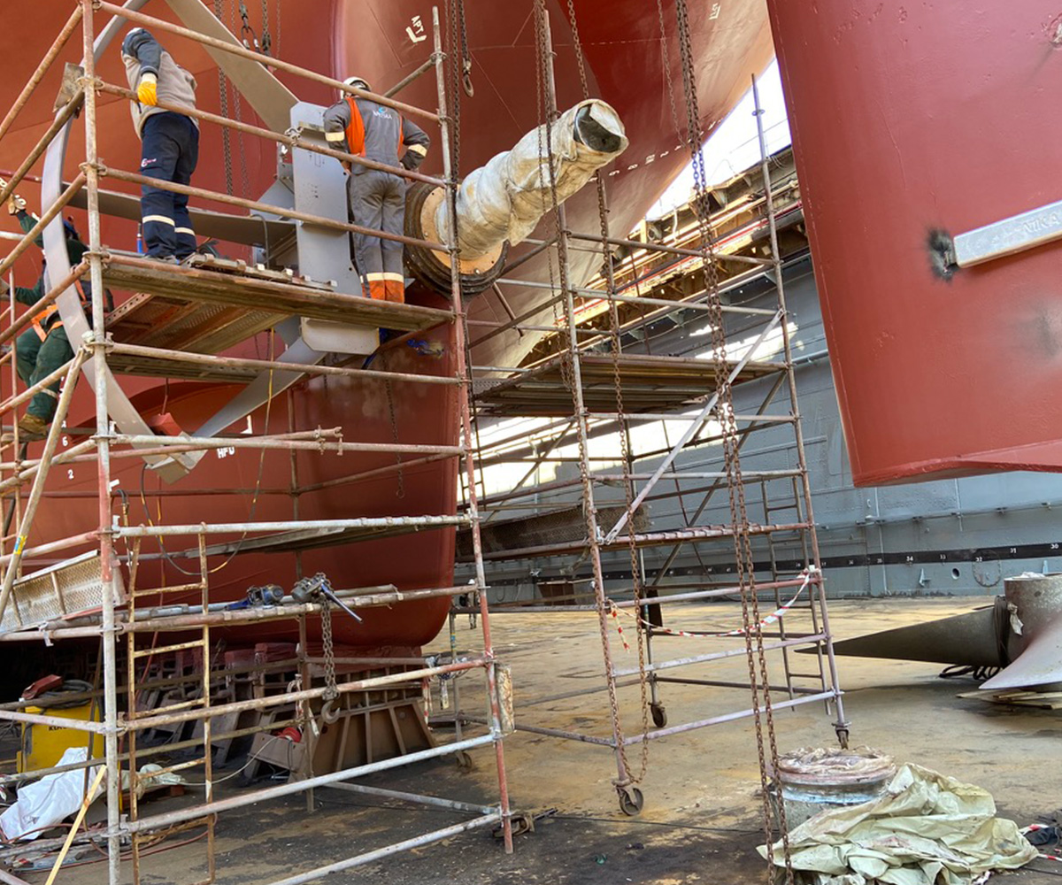Technicians working on a ship's propulsion system at the dry dock.