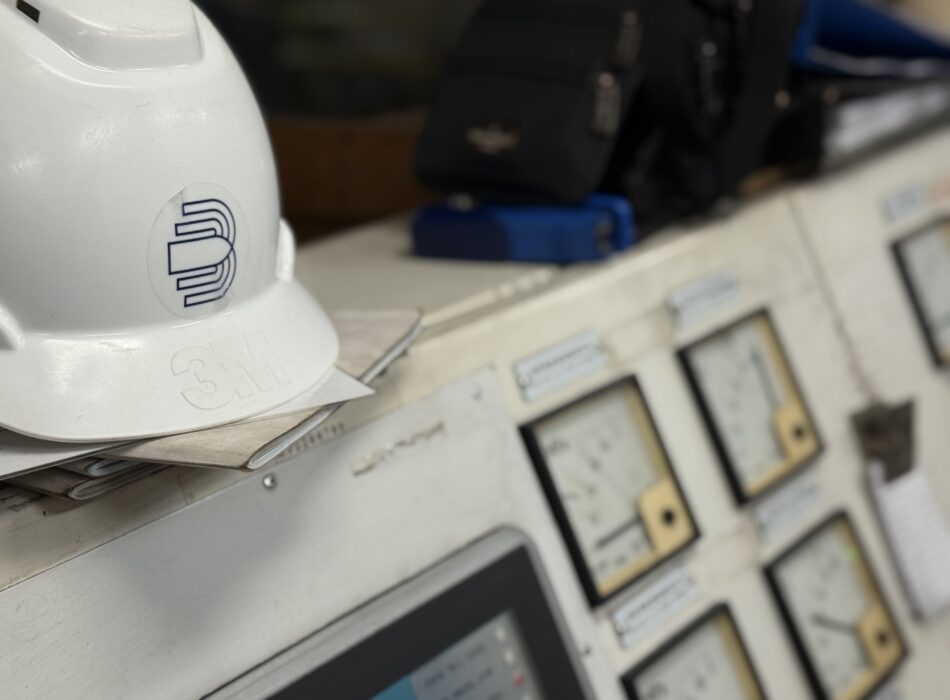 Marine engineer’s safety helmet placed on generator control panel during on-site synchronization and repair operation.